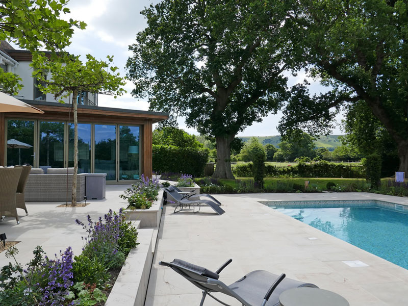 Table top trees. Large stone terrace. Garden design. Swimming pool. Automatic cover. South Downs National Park garden.